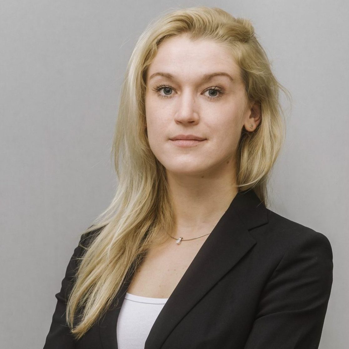 Die juristische Mitarbeiterin und Rechtsanwaltsassistentin der auf Einwanderungsrecht und Staatsbürgerschaftsrecht spezialisierten Kanzlei in Wien Julia Hertzberg blickt in die Kamera.